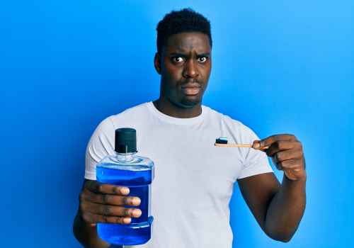 Black male against blue background holding blue mouthwash and a toothbrush