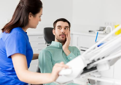 Man in dental chair next to female dentist for treatment for sensitive teeth