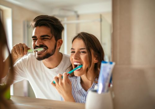 Man and woman brushing their teeth to prevent bad breath